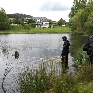 Drei Taucher der Wasserschutzpolizei suchen in einem Weiher in Hinterzarten nach einer vermissten Frau.